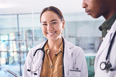 Buy stock photo Cropped shot of two young doctors working on a digital tablet while standing in the hospital