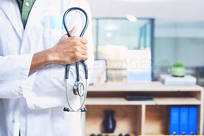 Buy stock photo Cropped shot of an unrecognizable male doctor standing with his stethoscope in the hospital