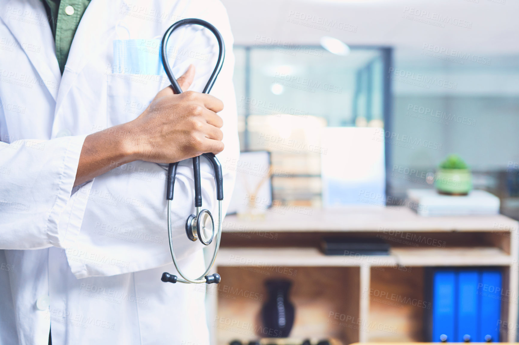 Buy stock photo Cropped shot of an unrecognizable male doctor standing with his stethoscope in the hospital