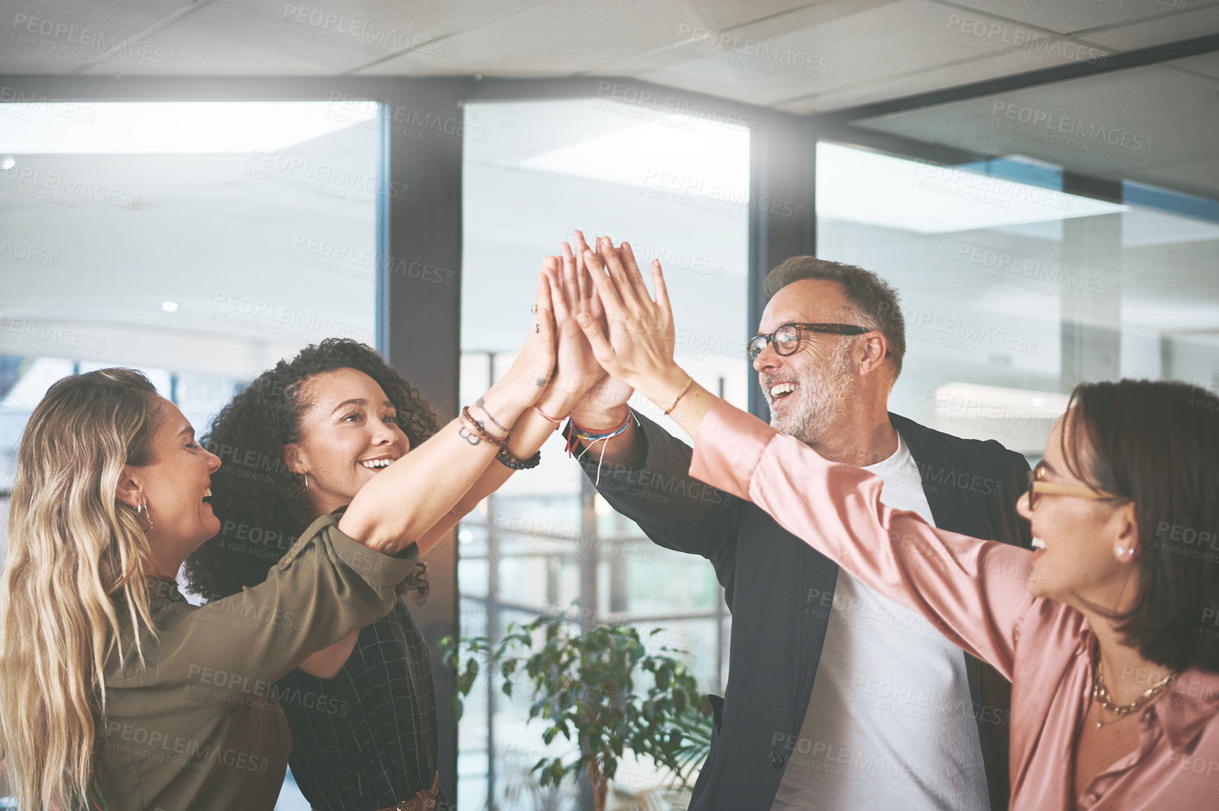 Buy stock photo Shot of a diverse group of businesspeople giving each other a high five during a meeting in the office