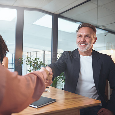 Buy stock photo Shot of a handsome mature businessman sitting and shaking a coworker's hand during a meeting in the office