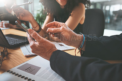 Buy stock photo Cropped shot of two unrecognizable businesspeople sitting together in the office and having a discussion while using a digital tablet