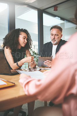 Buy stock photo Shot of two businesspeople sitting together in the office and having a discussion while using a digital tablet