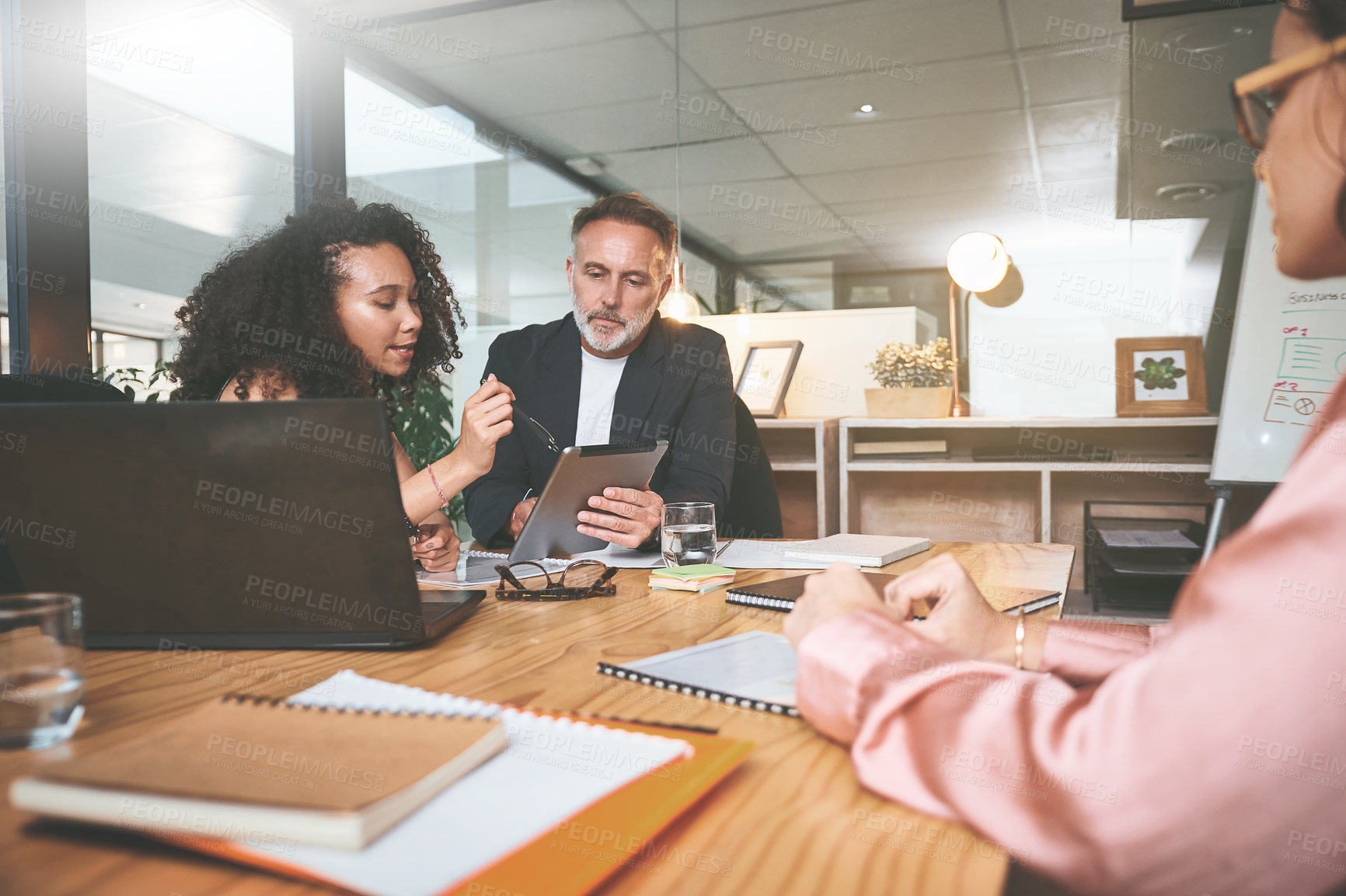 Buy stock photo Shot of two businesspeople sitting together in the office and having a discussion while using a digital tablet