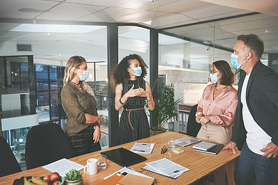 Buy stock photo Shot of a diverse group of businesspeople having a discussion during a meeting in the office while wearing face masks