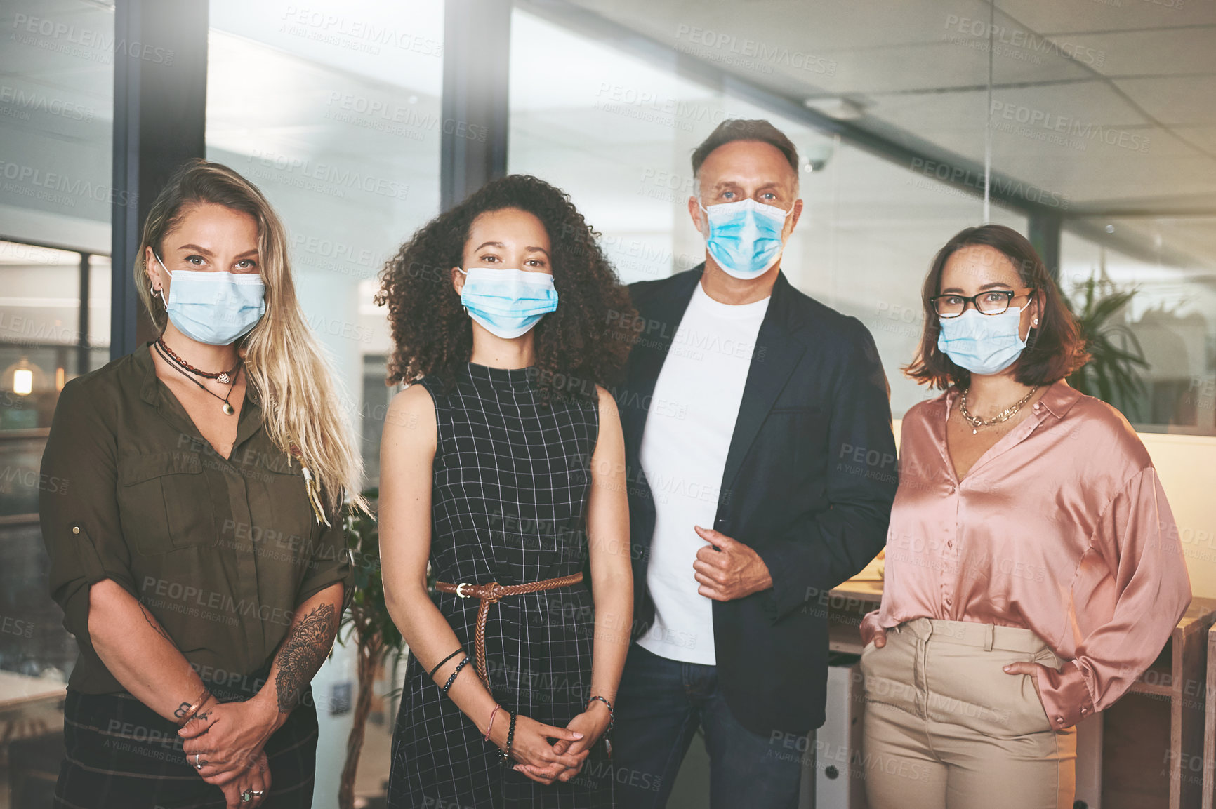 Buy stock photo Shot of a diverse group of businesspeople standing together in the office and wearing face masks