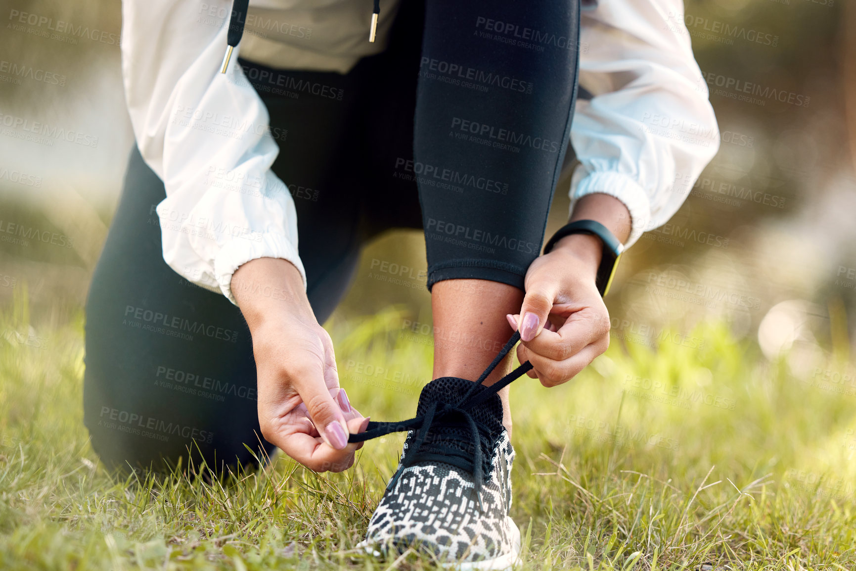 Buy stock photo Closeup shot of an unrecognisable woman tying her shoelaces while exercising outdoors