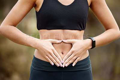 Buy stock photo Closeup shot of an unrecognisable woman making a heart shape with her hands on her stomach while exercising outdoors