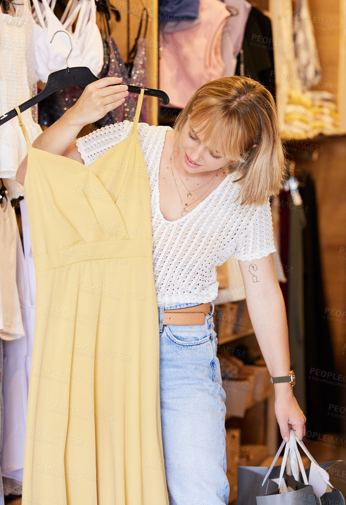 Buy stock photo Shot of an attractive young woman checking an item of clothing in a store