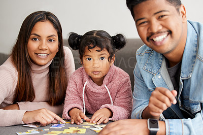 Buy stock photo Shot of young parents helping their daughter build a puzzle