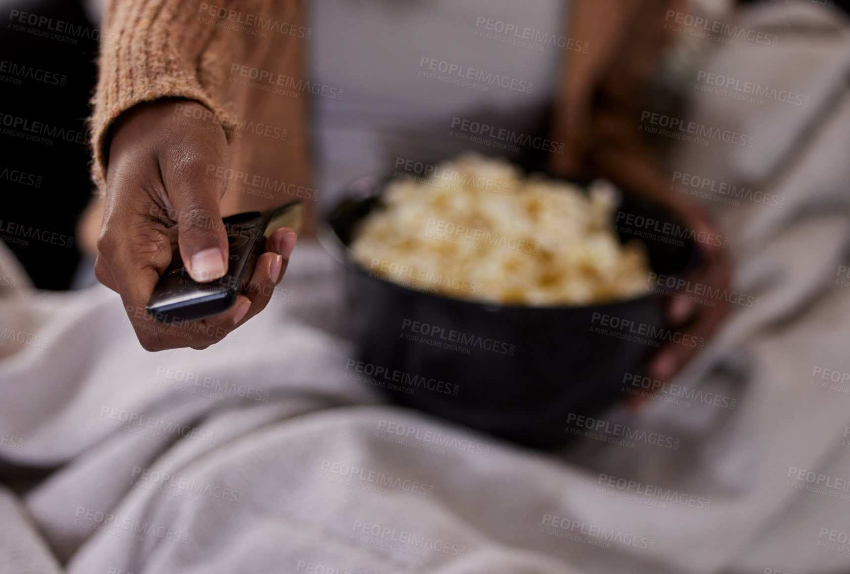 Buy stock photo Hand, remote and watching tv with popcorn in home on sofa with click, choice and decision for movie. Person, eating and press button to start film, streaming service and show with snack in house