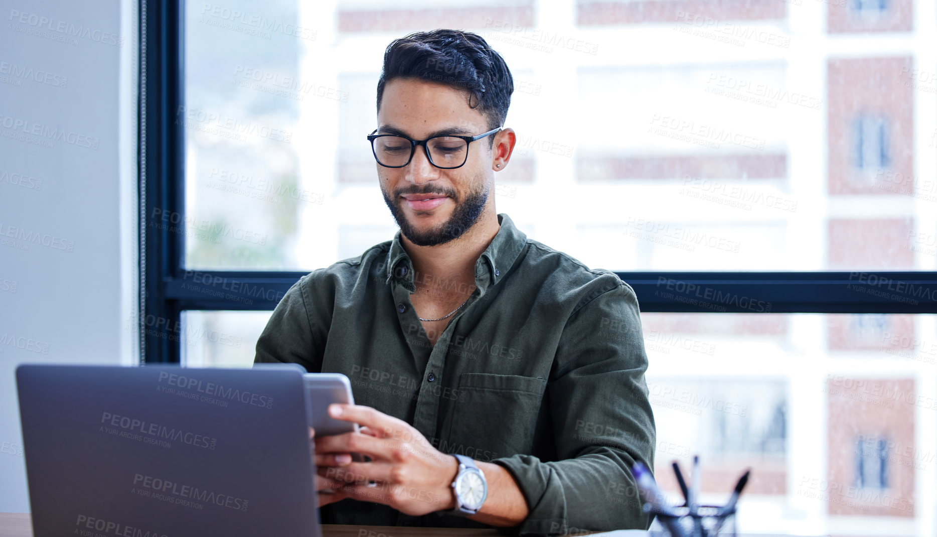 Buy stock photo Laptop, phone and businessman with glasses in office for creative project with copywriting. Smile, technology and professional writer or editor from Mexico with computer and cellphone in workplace.