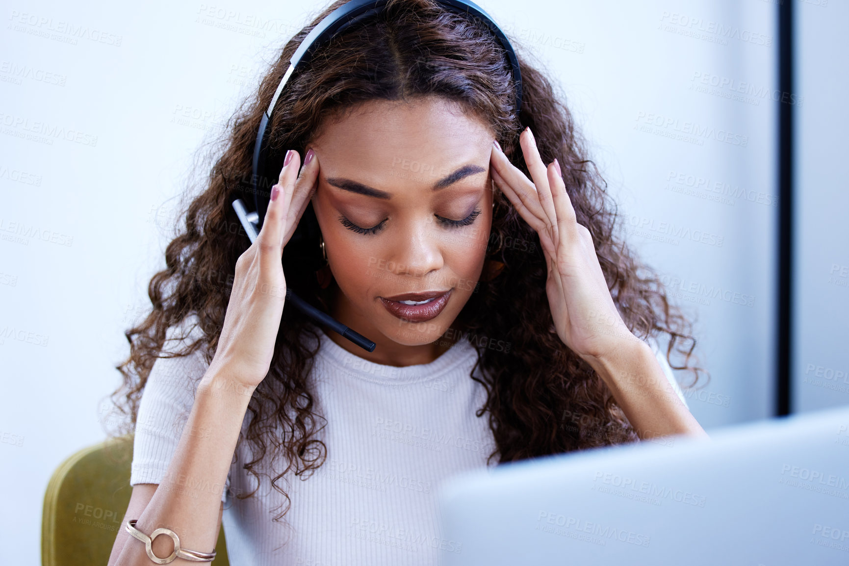 Buy stock photo Shot of a young call centre agent looking stressed out while working in an office