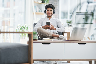 Buy stock photo Portrait of a young businessman using a cellphone while working in an office