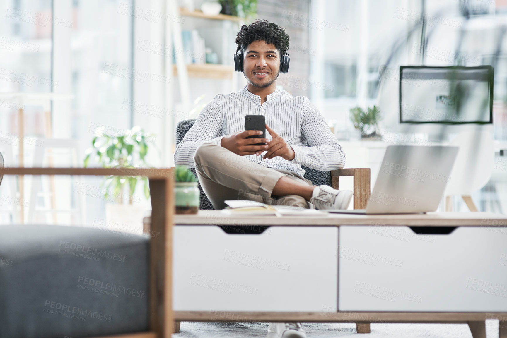 Buy stock photo Portrait of a young businessman using a cellphone while working in an office