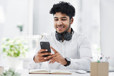 Buy stock photo Shot of a young businessman using a cellphone in an office