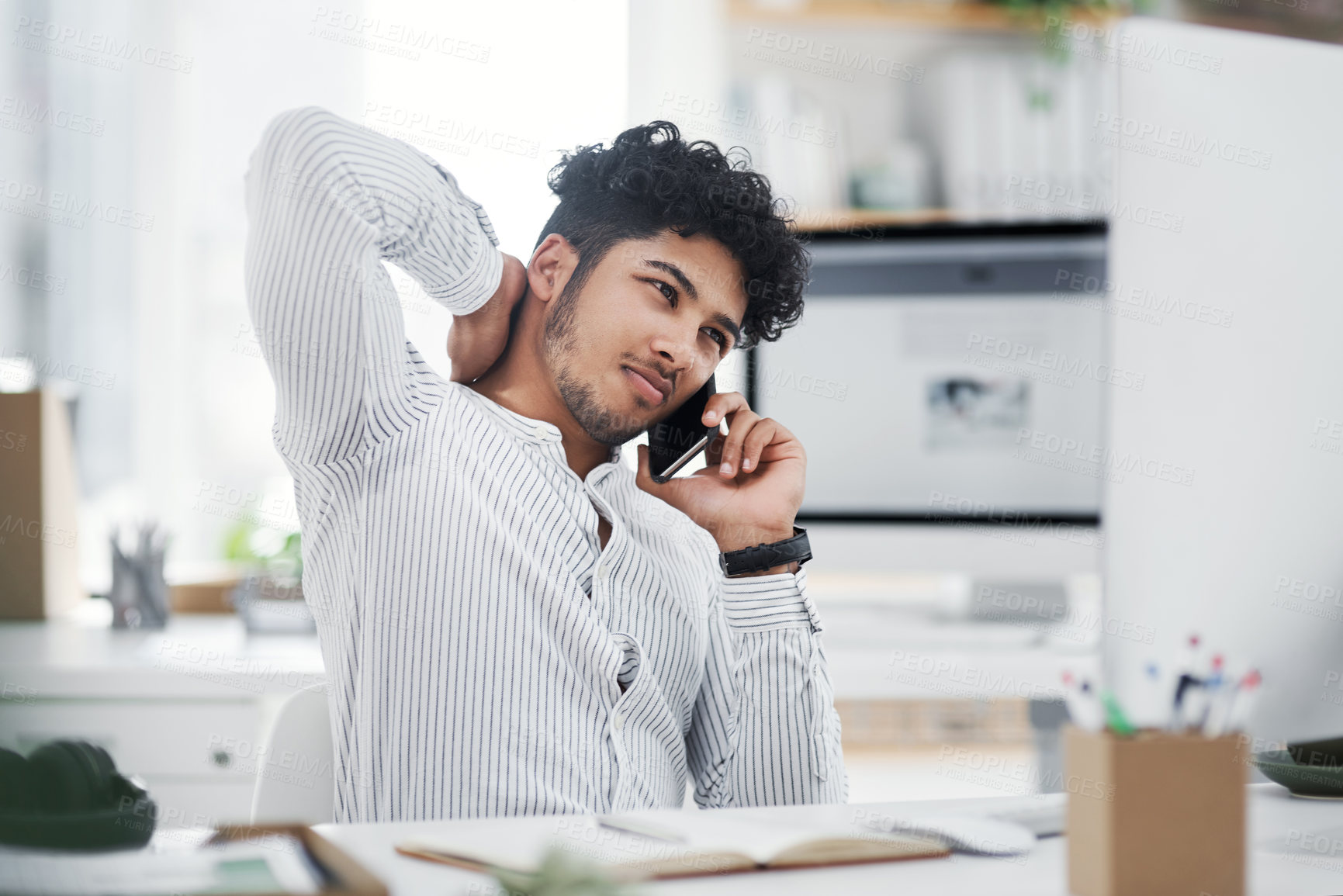 Buy stock photo Shot of a young businessman looking stressed out while talking on a cellphone in an office