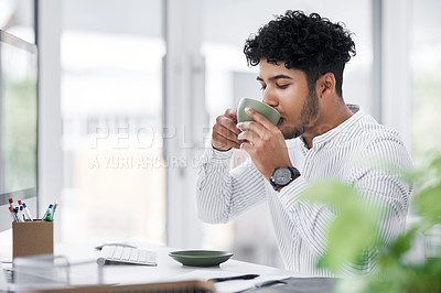 Buy stock photo Portrait of a young businessman drinking coffee while working in an office