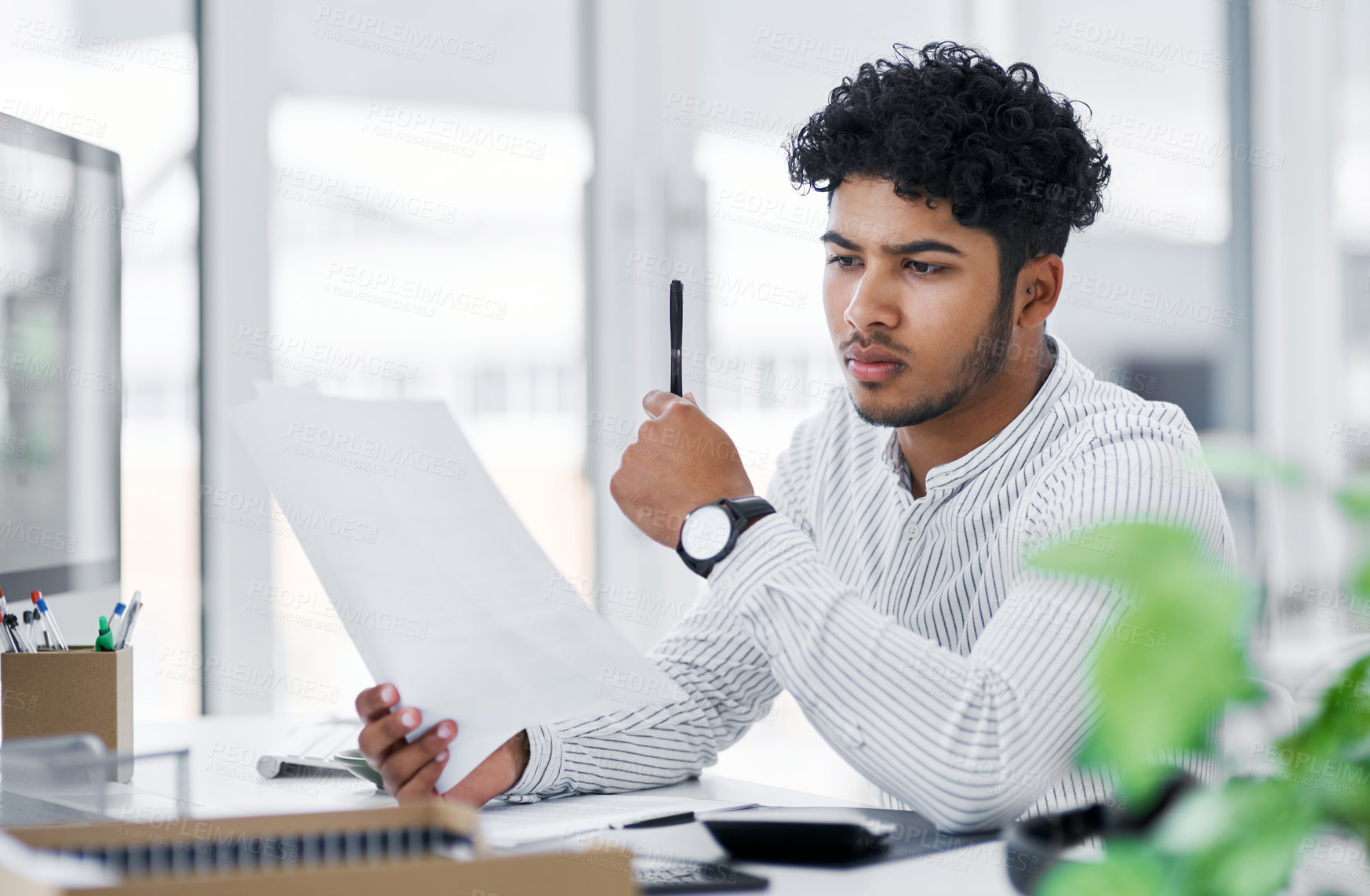 Buy stock photo Shot of a young businessman going through paperwork in an office