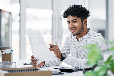 Buy stock photo Shot of a young businessman going through paperwork in an office