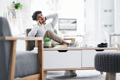 Buy stock photo Shot of a young businessman looking stressed out while talking on a cellphone in an office