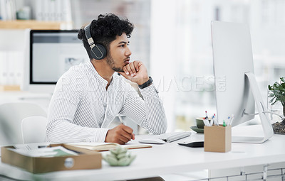 Buy stock photo Shot of a young businessman looking thoughtful while working on a computer in an office