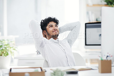 Buy stock photo Shot of a young businessman sitting with his hands behind his head while working in an office