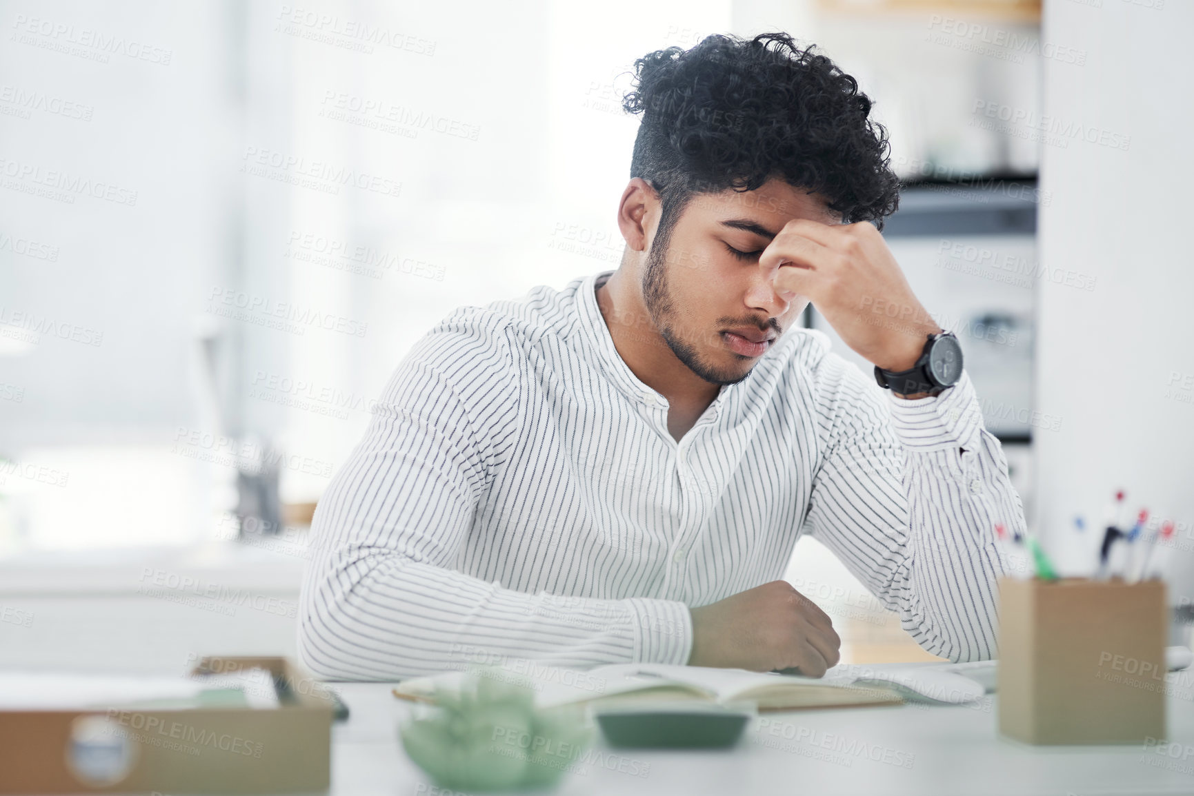 Buy stock photo Shot of a young businessman looking stressed out while working in an office