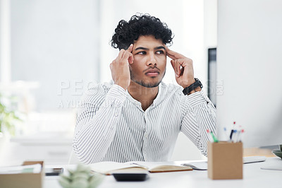 Buy stock photo Shot of a young businessman looking stressed out while working in an office