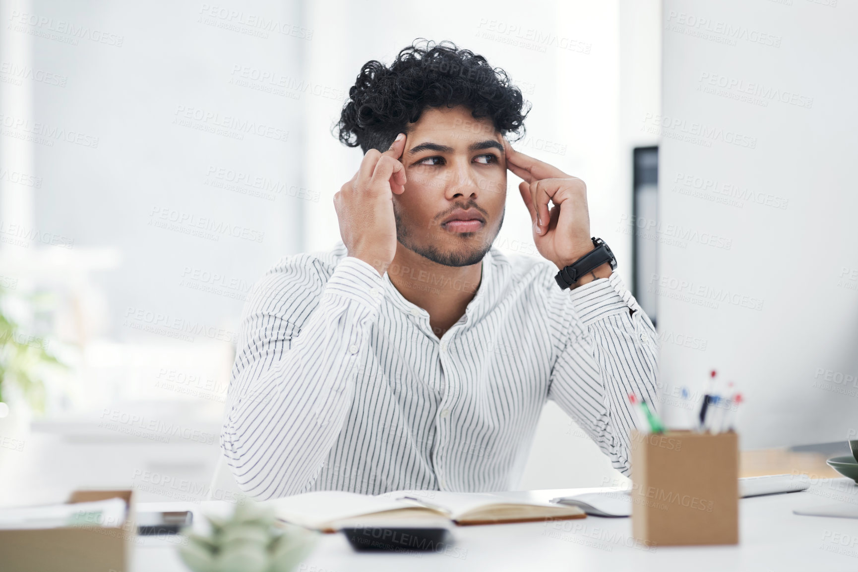 Buy stock photo Shot of a young businessman looking stressed out while working in an office