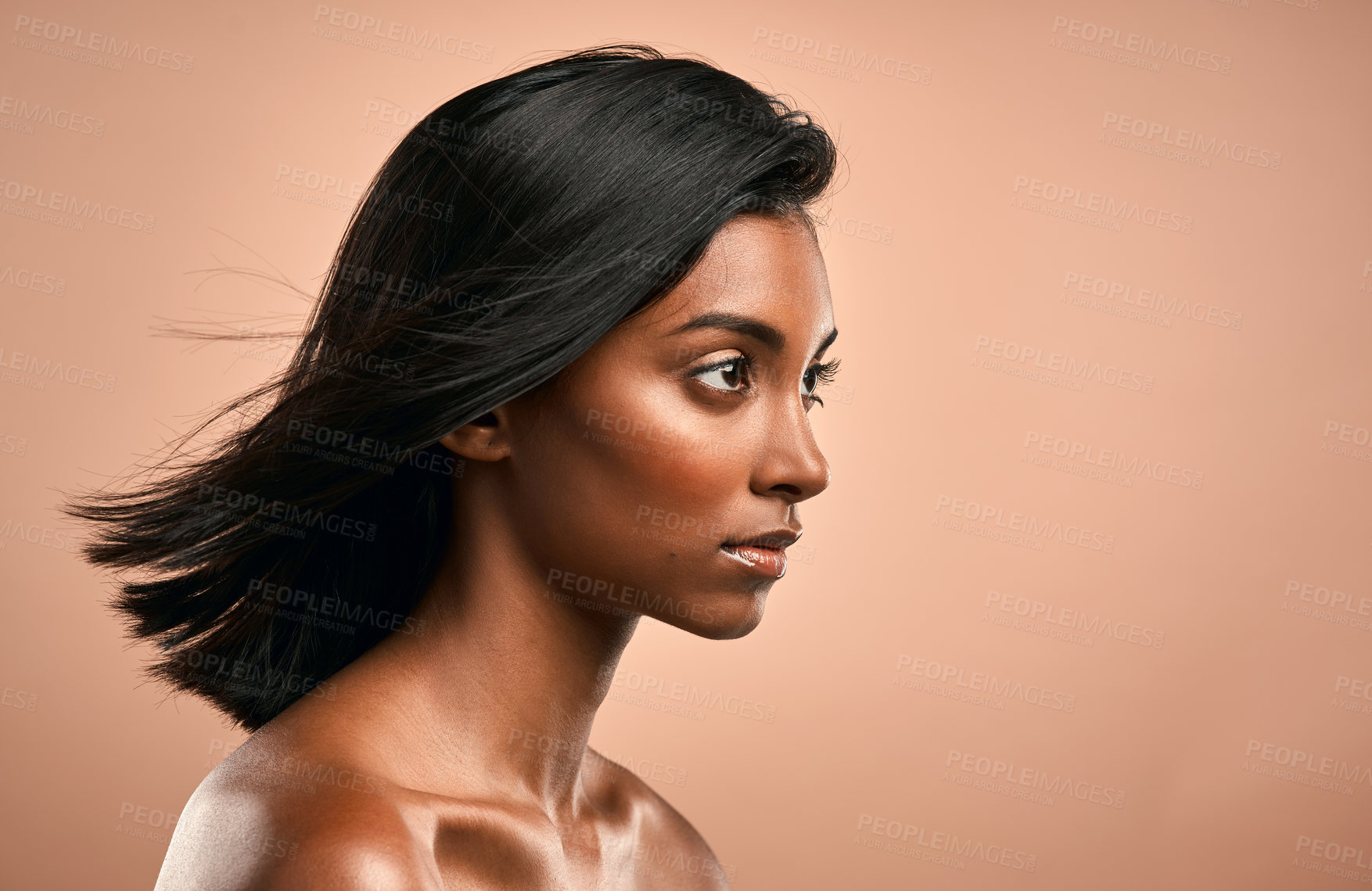 Buy stock photo Side shot of a beautiful young woman posing against a brown background