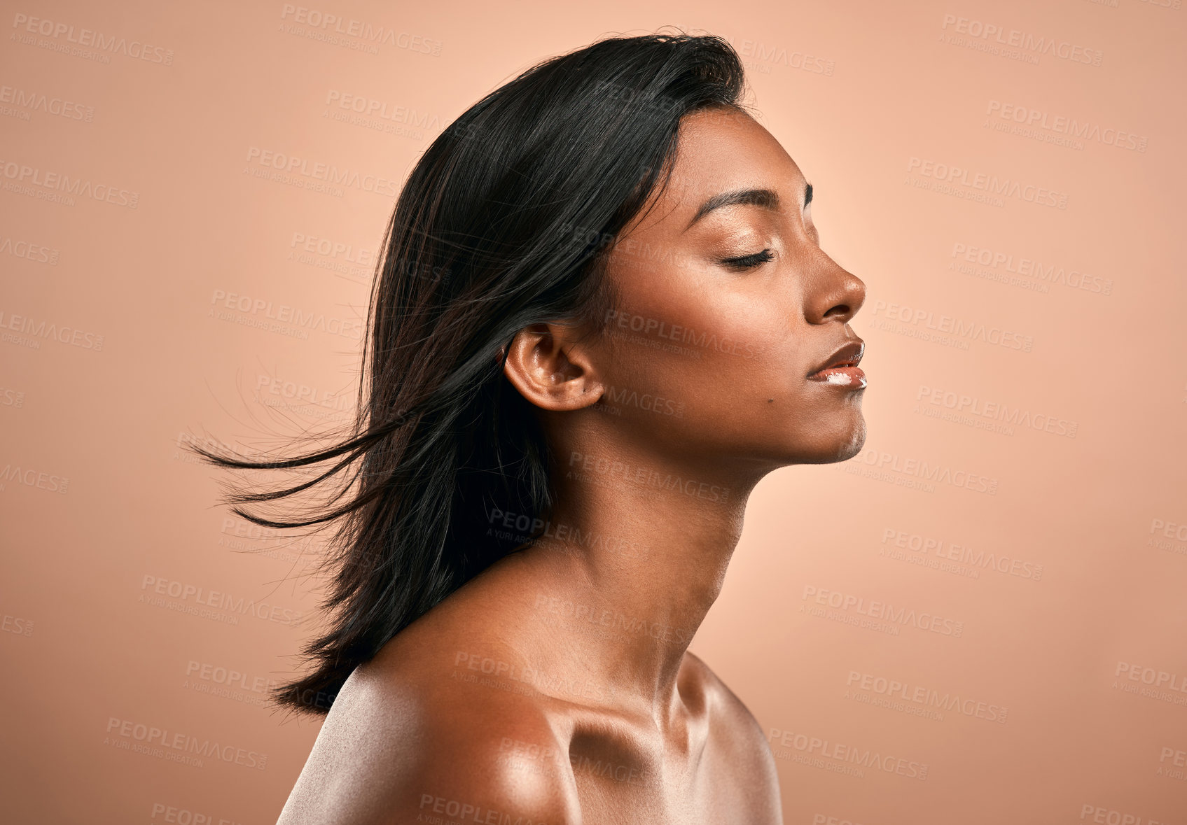 Buy stock photo Side shot of a beautiful young woman posing against a brown background