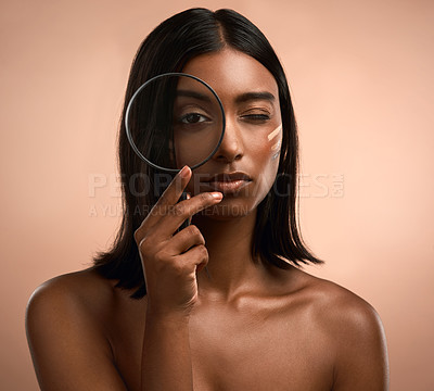 Buy stock photo Portrait of a beautiful young woman holding a magnifying glass while posing against a brown background