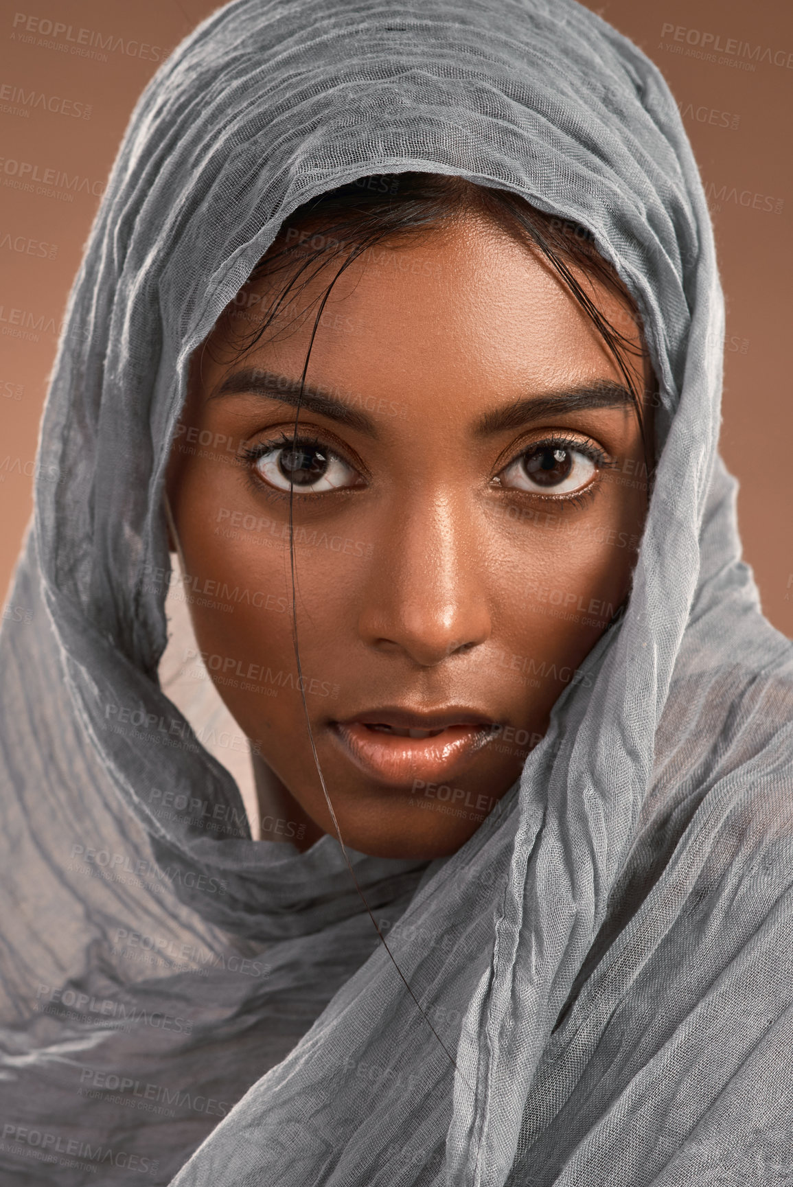 Buy stock photo Portrait of an attractive young woman wearing a head scarf against a brown background