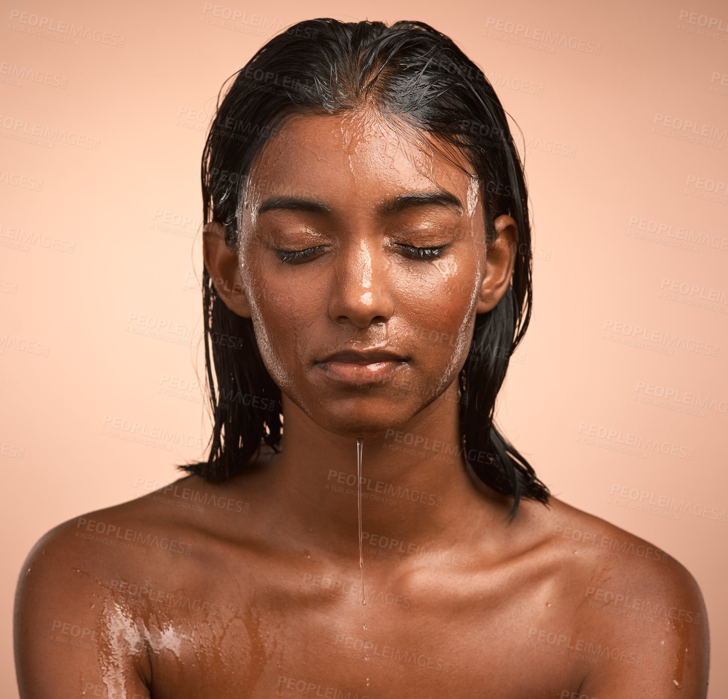 Buy stock photo Shot of a young attractive woman doing her daily skincare routine against a brown background