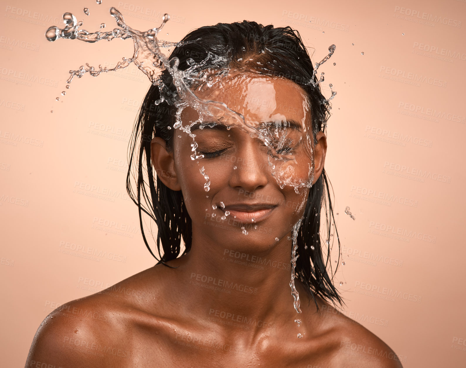 Buy stock photo Shot of a young attractive woman doing her daily skincare routine against a brown background