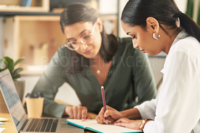 Buy stock photo Shot of two female businesswoman making notes in a notebook