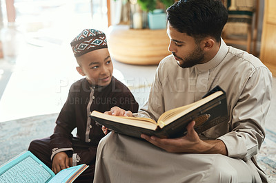 Buy stock photo Shot of a young muslim man and his son reading in the lounge at home