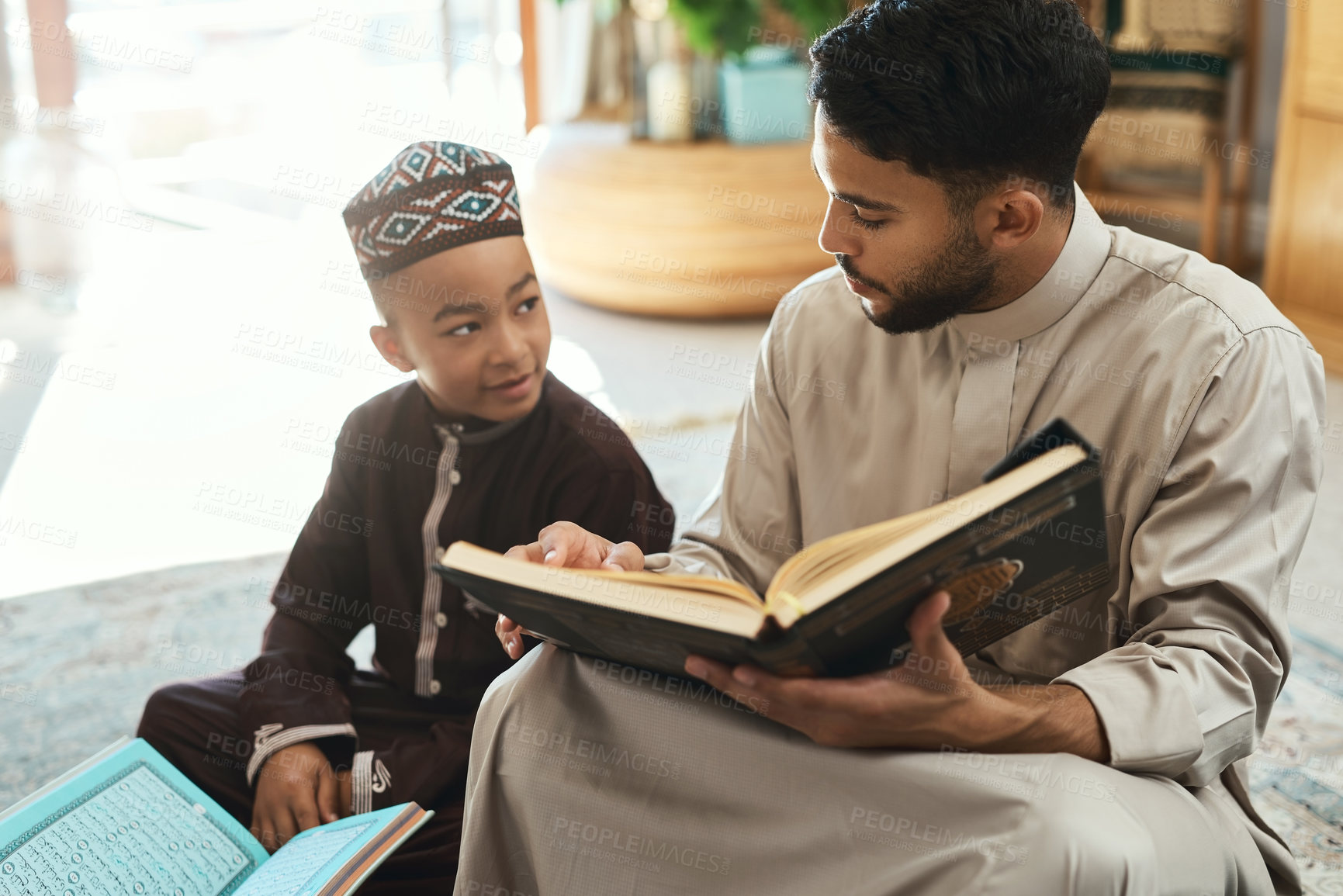 Buy stock photo Shot of a young muslim man and his son reading in the lounge at home