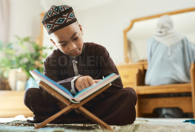Buy stock photo Shot of a young muslim boy reading in the lounge at home