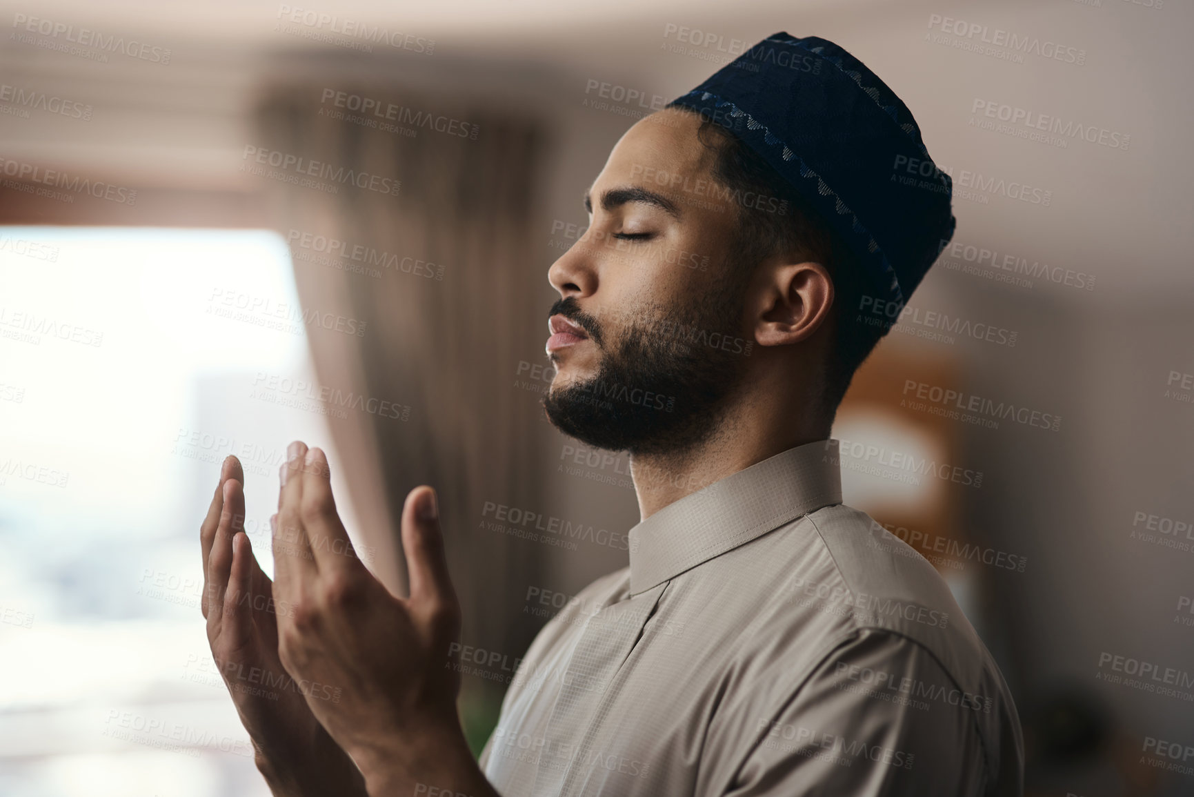 Buy stock photo Shot of a young muslim man praying in the lounge at home