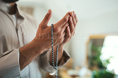 Buy stock photo Shot of a unrecognizable muslim man praying in the lounge at home