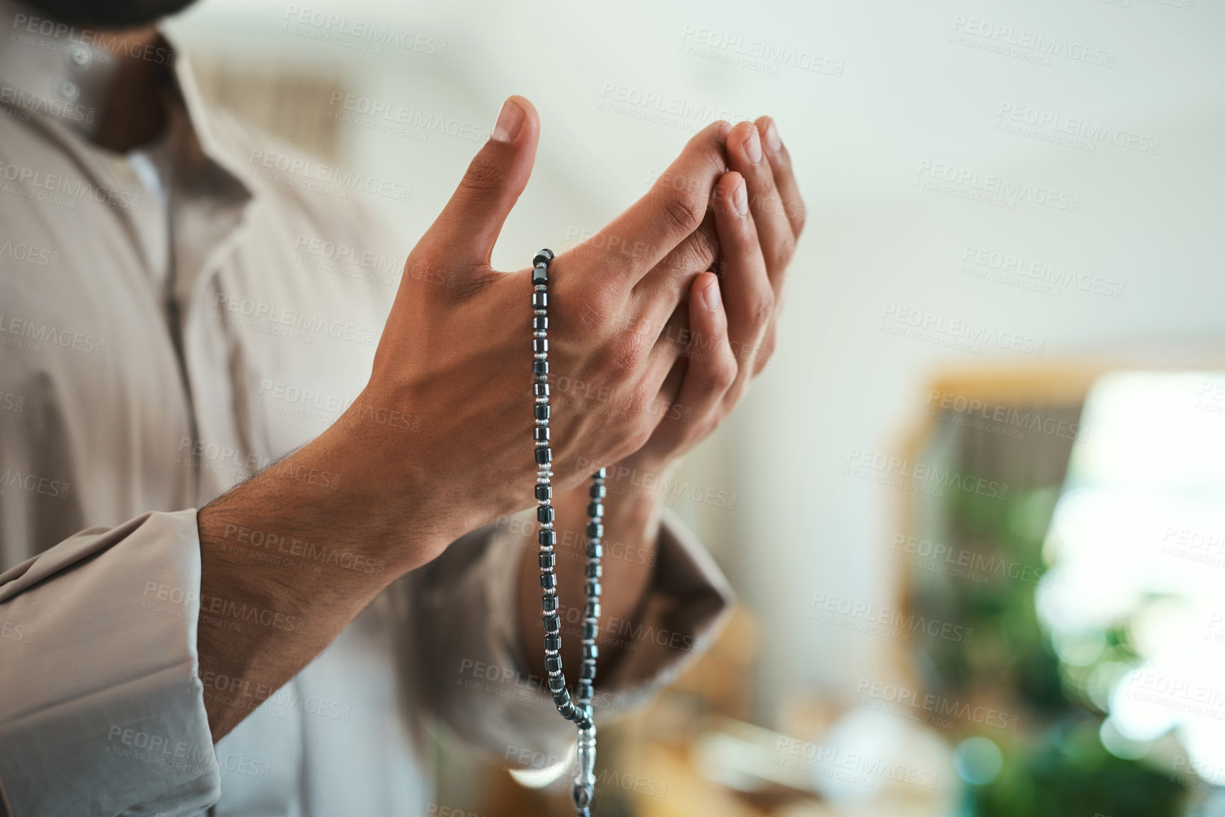 Buy stock photo Shot of a unrecognizable muslim man praying in the lounge at home