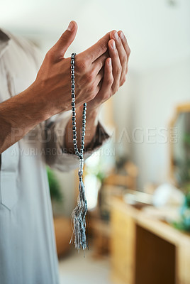 Buy stock photo Shot of a unrecognizable muslim man praying in the lounge at home