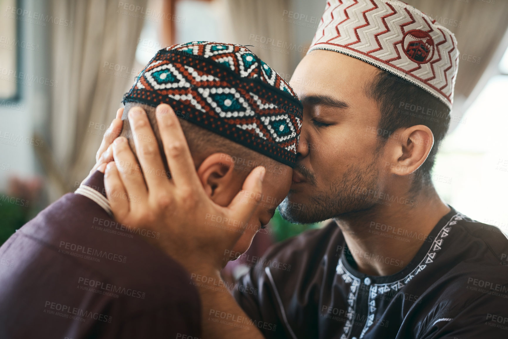 Buy stock photo Shot of a young muslim father affectionately giving his son a forehead kiss