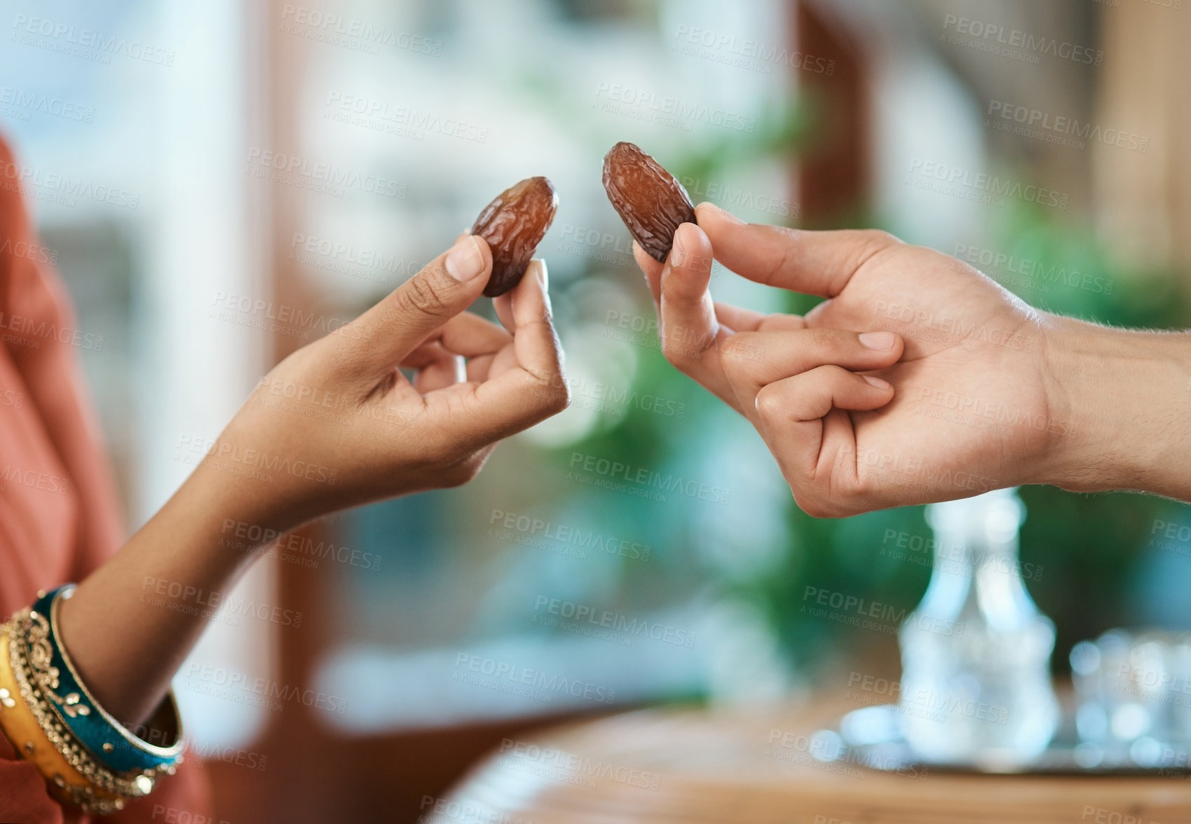 Buy stock photo Hands, muslim and couple with dates in home for Ramadan, gratitude and islamic tradition. People, holy water and breaking fast with fruit, religious practice and nutrition snack for iftar celebration