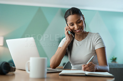 Buy stock photo Shot of a young woman writing in a notebook while on a call at home