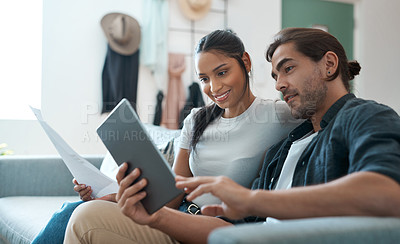 Buy stock photo Shot of a young couple doing paperwork while using a digital tablet at home