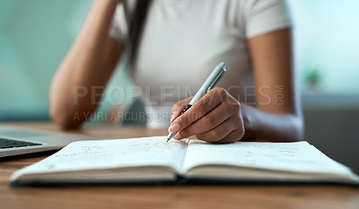 Buy stock photo Shot of a young woman writing in a notebook at home