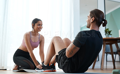 Buy stock photo Full length shot of an attractive young woman helping her boyfriend with his situps during their workout at home